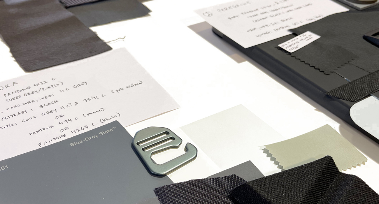 Flat lay showing layered materials and construction elements used in a soft good prototype textile system, including shell fabric, foam, mesh, reinforcement, and webbing.